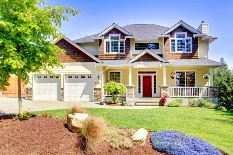 Two-story craftsman-style home with a red front door and landscaped yard