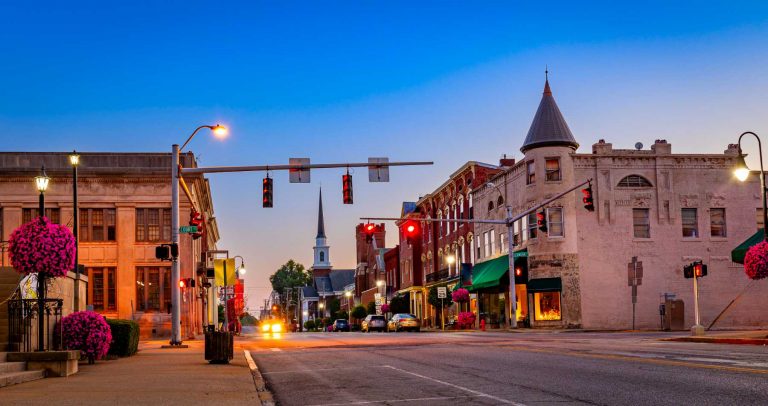 Downtown Versailles, Kentucky at dusk, with historic storefronts and a church steeple